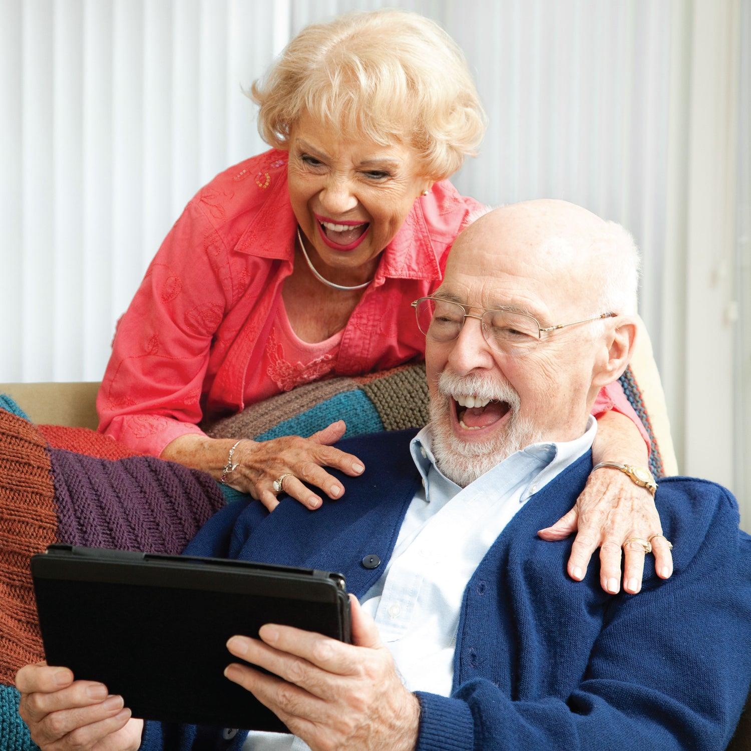 Older couple laughing together while using iPad confidently alone